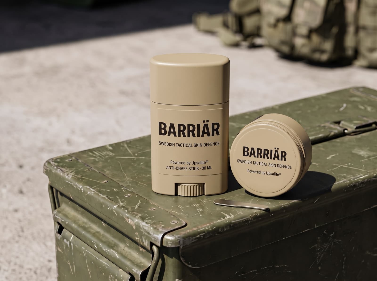 Barriär anti-chafe stick and jar in matte sand-beige packaging on a scratched olive-green ammunition box in hard sunlight, both printed with the Barriär wordmark in Saira condensed over Swedish Tactical Skin Defence
