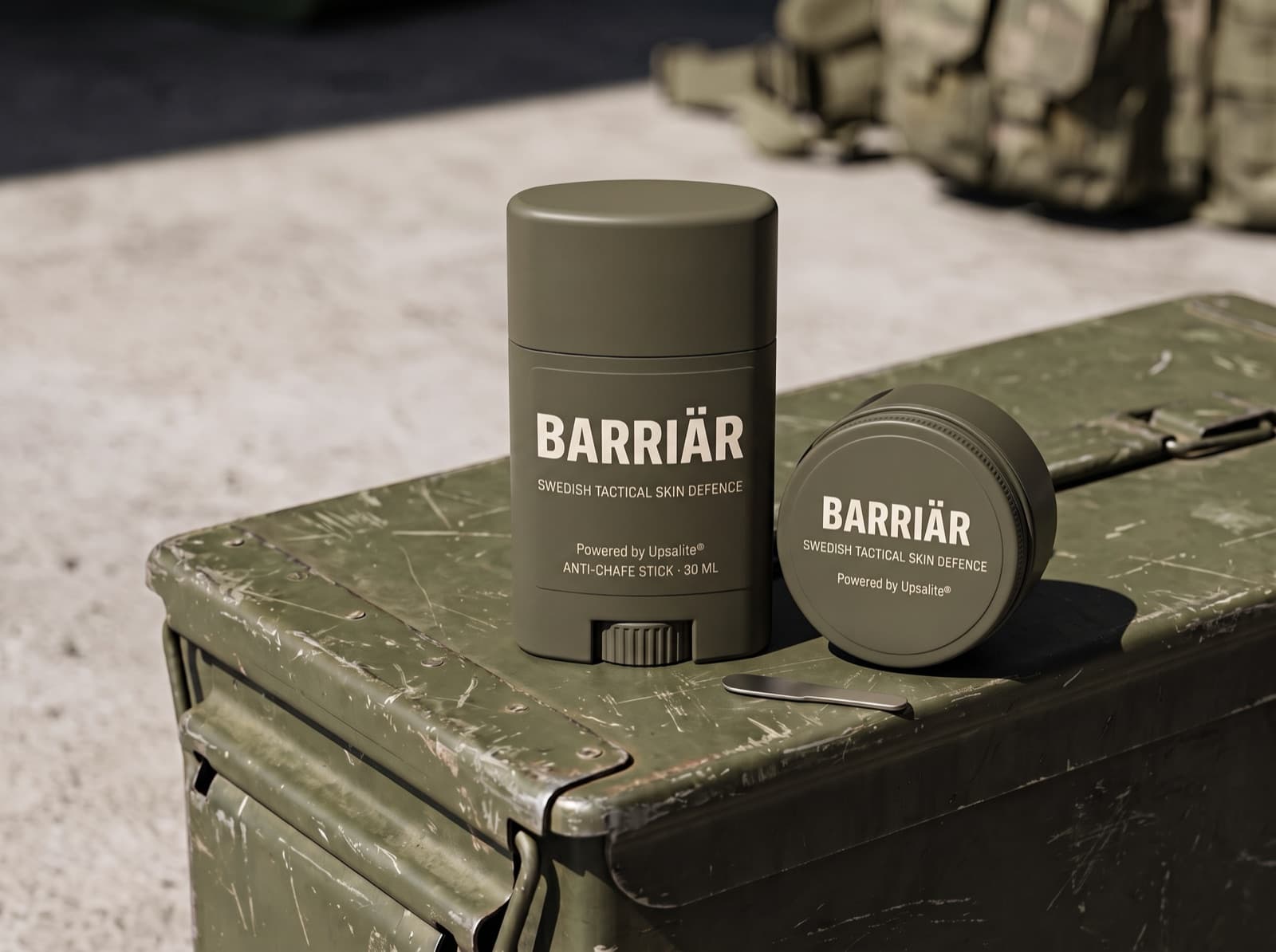 Barriär anti-chafe stick and jar in matte olive packaging on a scratched olive-green ammunition box in hard sunlight, both printed with the Barriär wordmark in Saira condensed over Swedish Tactical Skin Defence