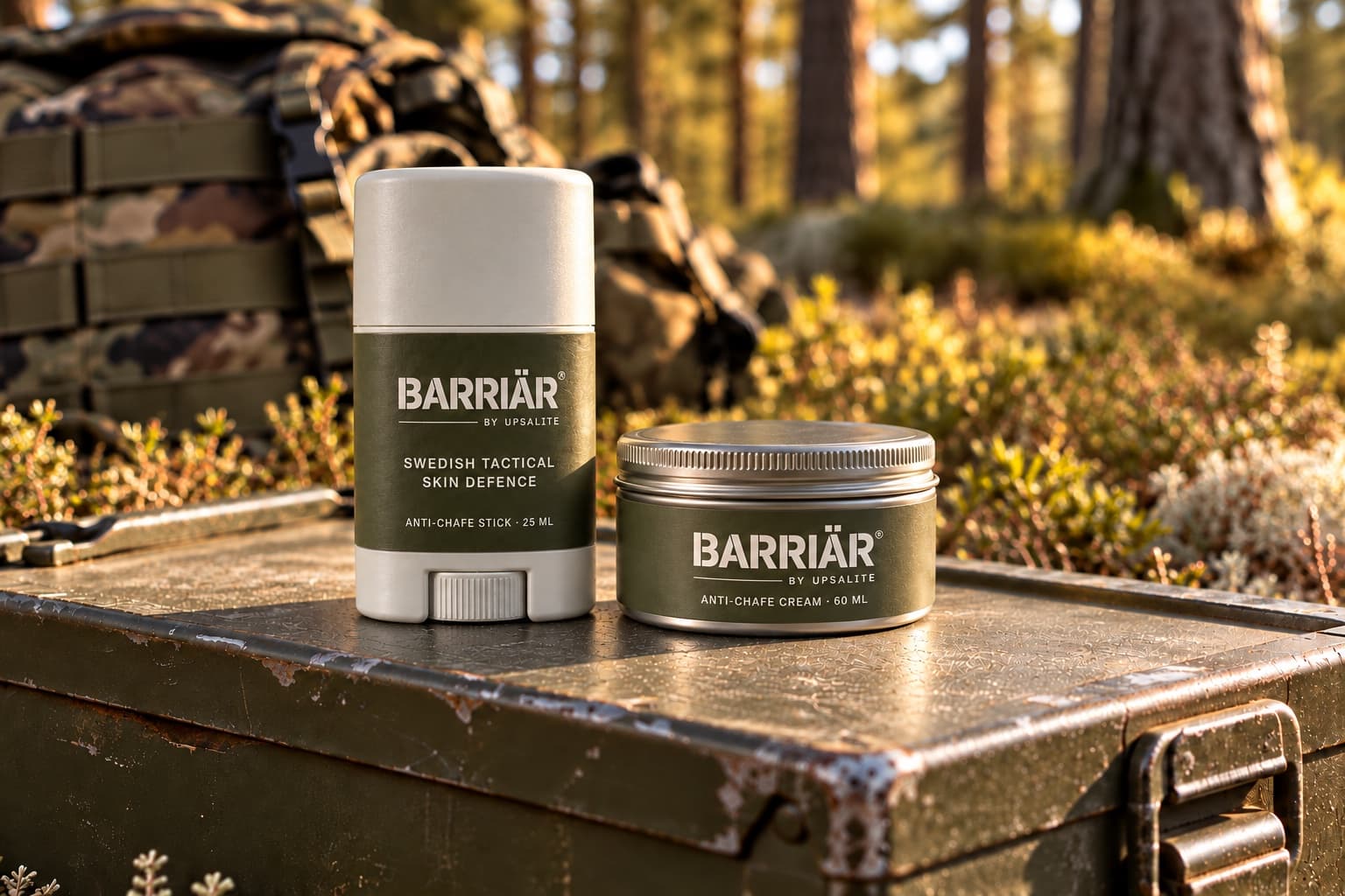 Barriär Anti-Chafe Stick 25 ml, a white stick with an olive label, and the wider, lower Anti-Chafe Cream 60 ml aluminium tin with an olive sticker, both printed in white with the Barriär by Upsalite wordmark, on a worn olive ammunition box in a sunlit pine forest with a camouflage rucksack behind